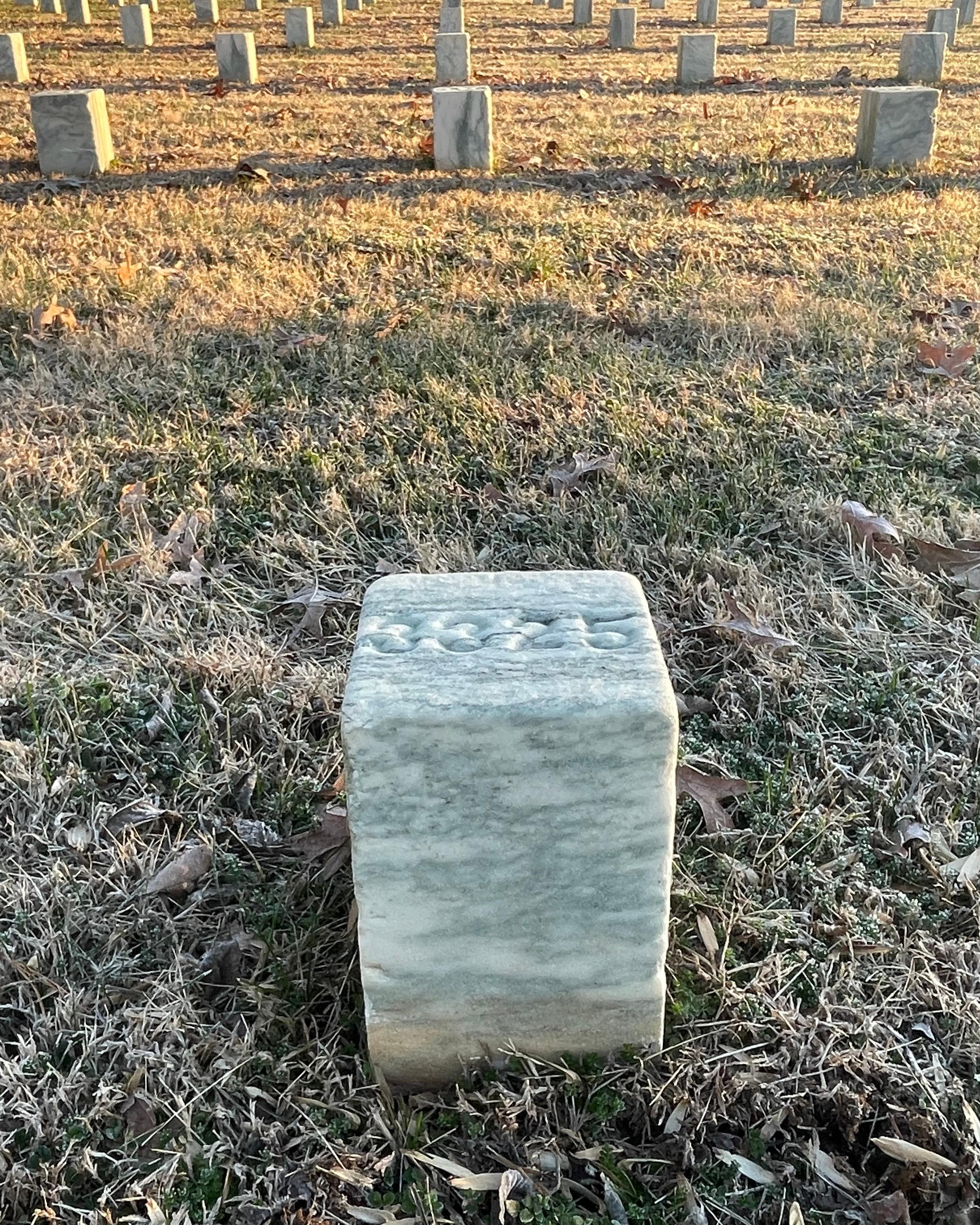 A white marble grave marker with a number on top.