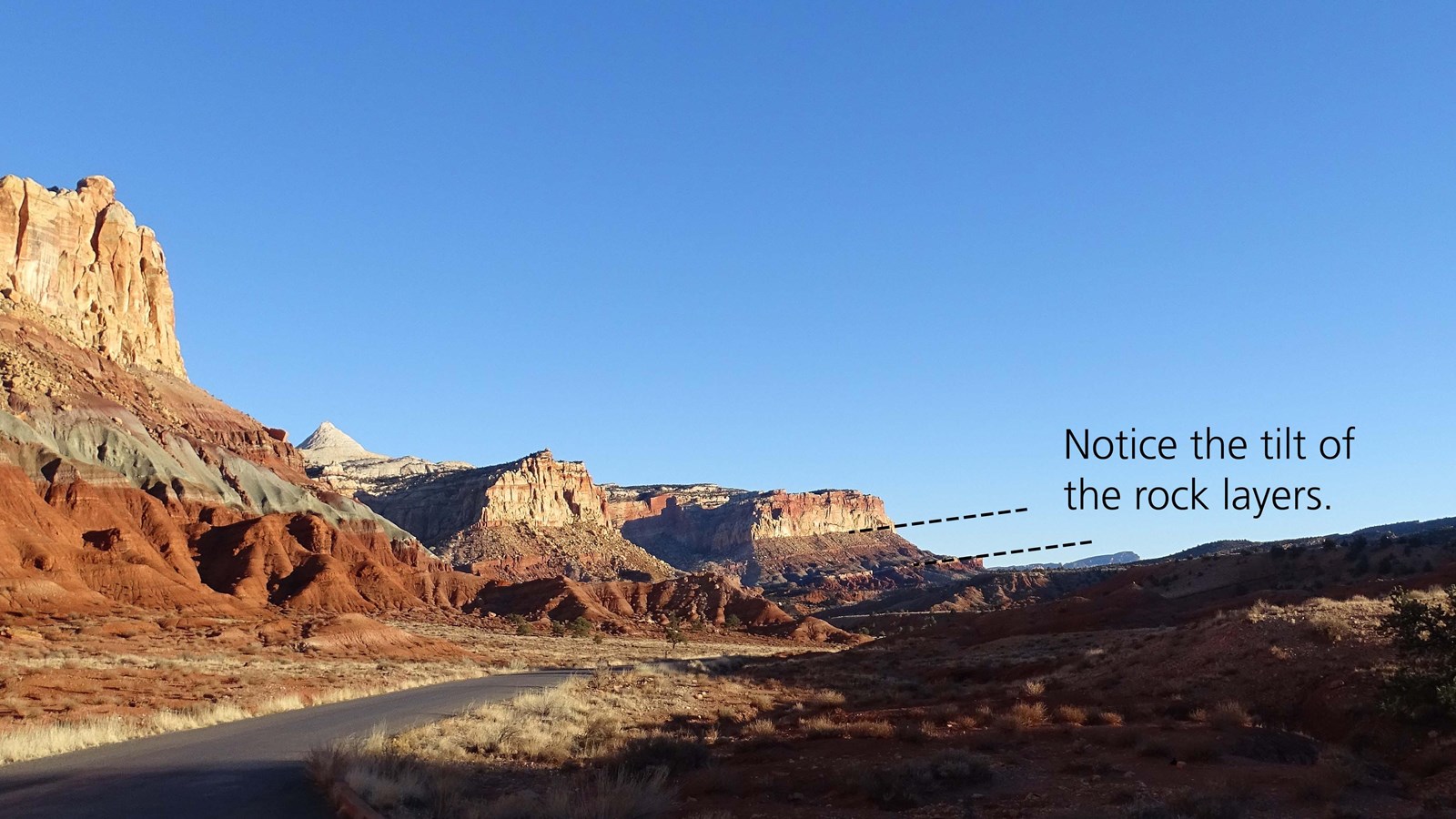 Banded red-brown cliffs that tilt down toward the east at about a 15 degree angle.