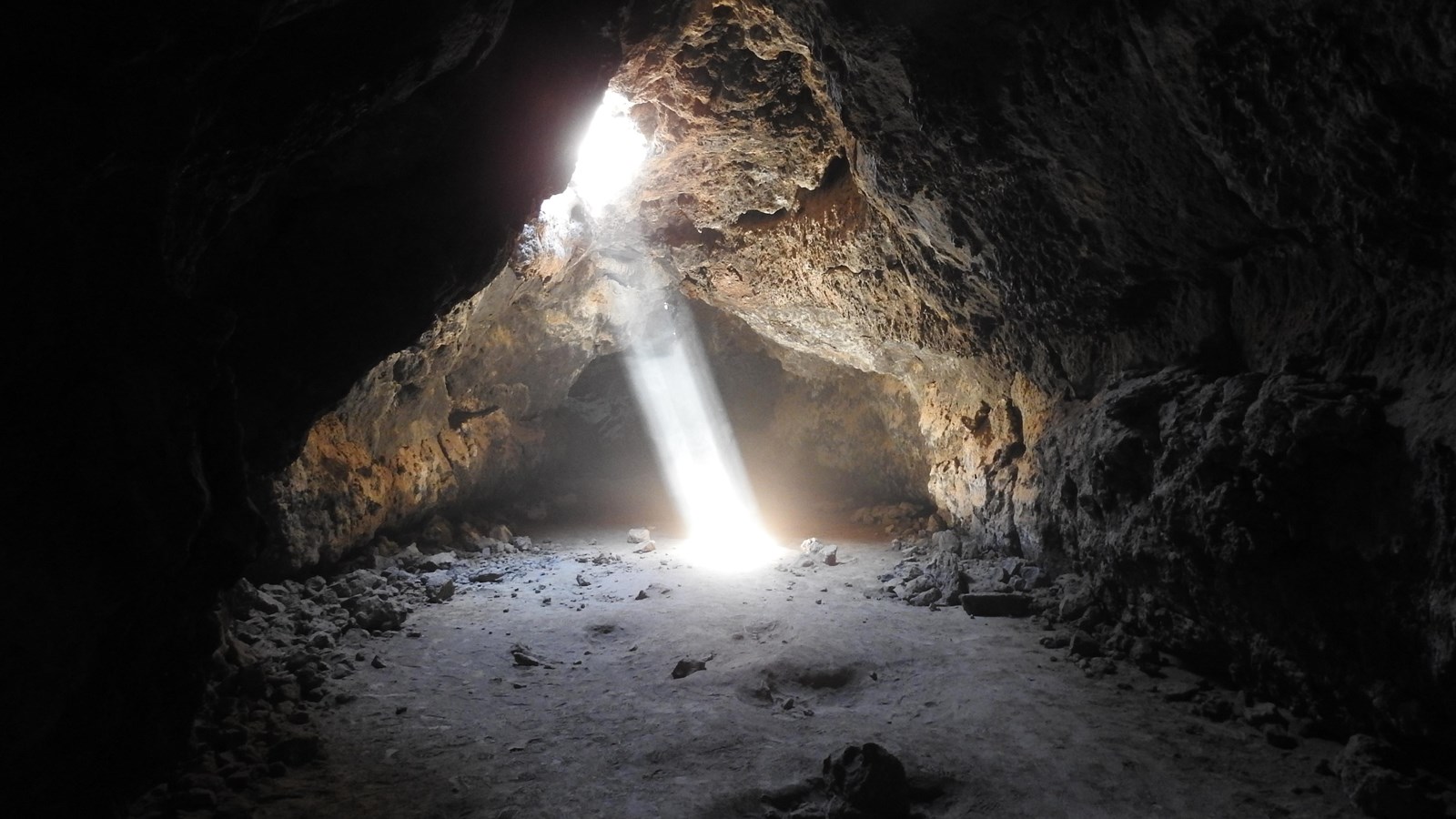 A beam of light shines down from above, illuminating rock walls