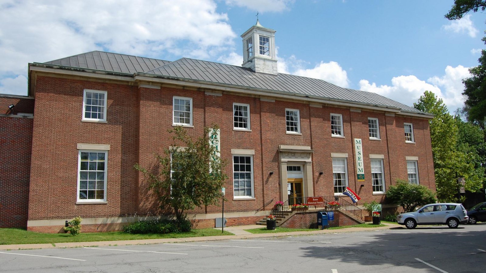 A two story brick building with a cupola. It has seven windows in the top row.  