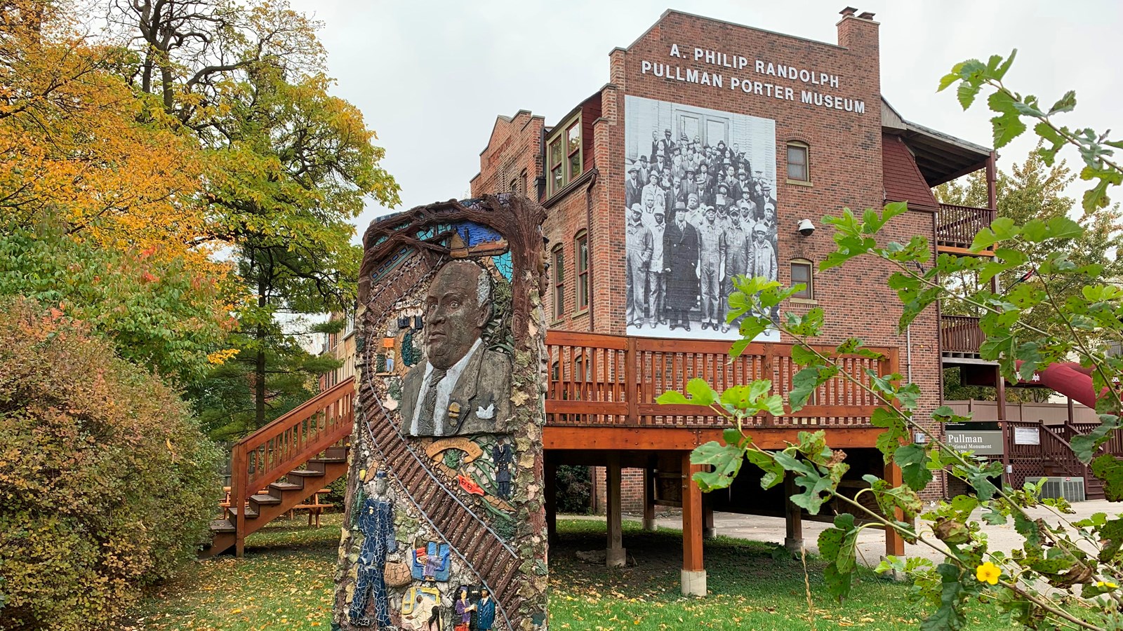 A three story tall brown brick building with a large photo of the Pullman Porters\' union and statue.