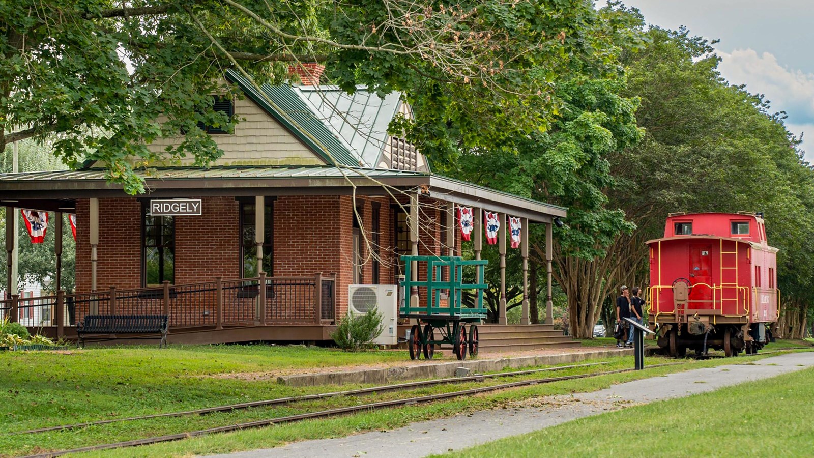 Historic train station with a red caboose and green surroundings.
