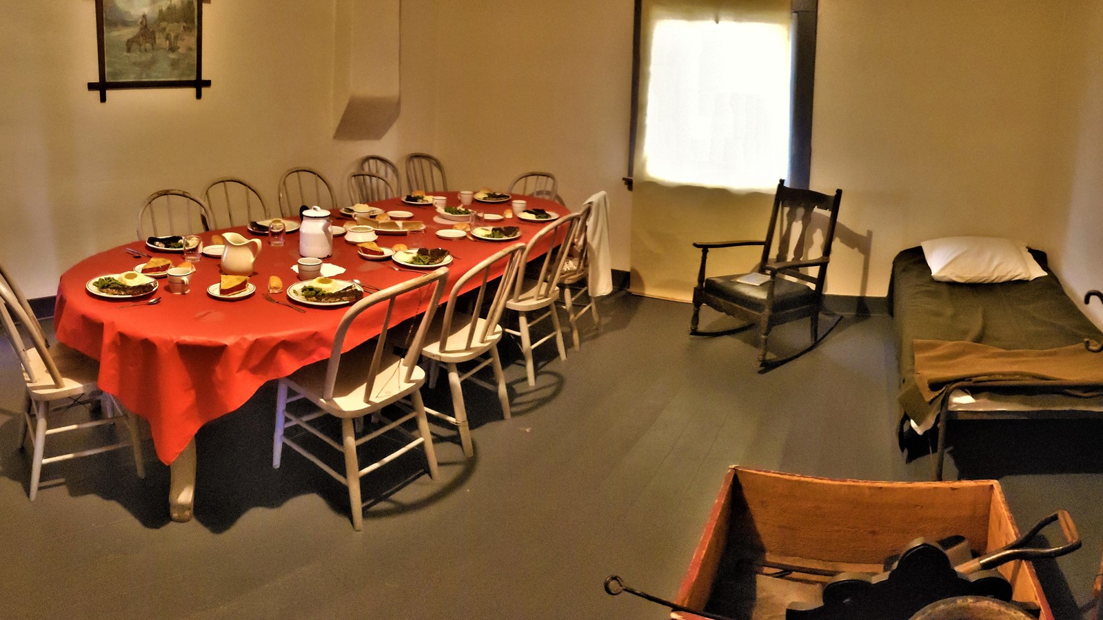 A long oval table with a red table cover is set with plates and dishes for 10 people.