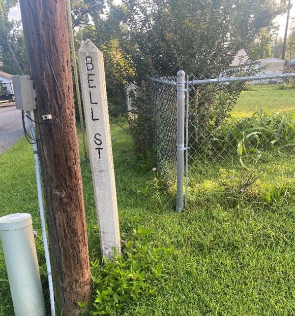 Verticle 5 foot marker with BELL ST carved in it.