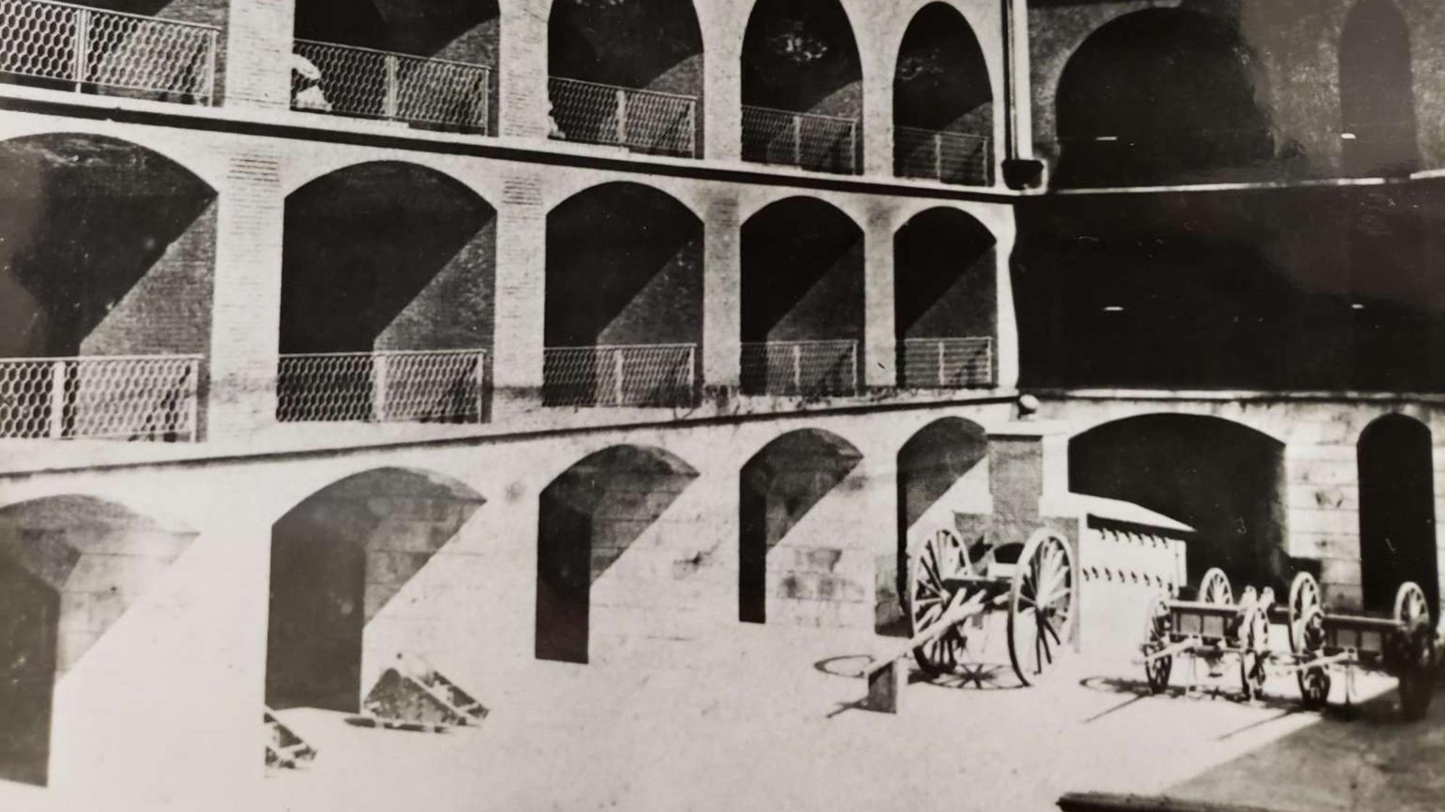 Cannon sit in a courtyard surrounded by three tiers of brick archways.