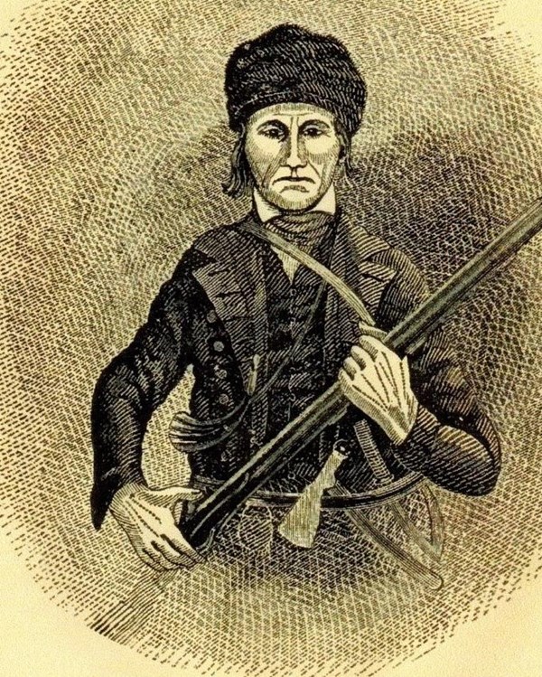 An older man with a fur cap and holding a musket.