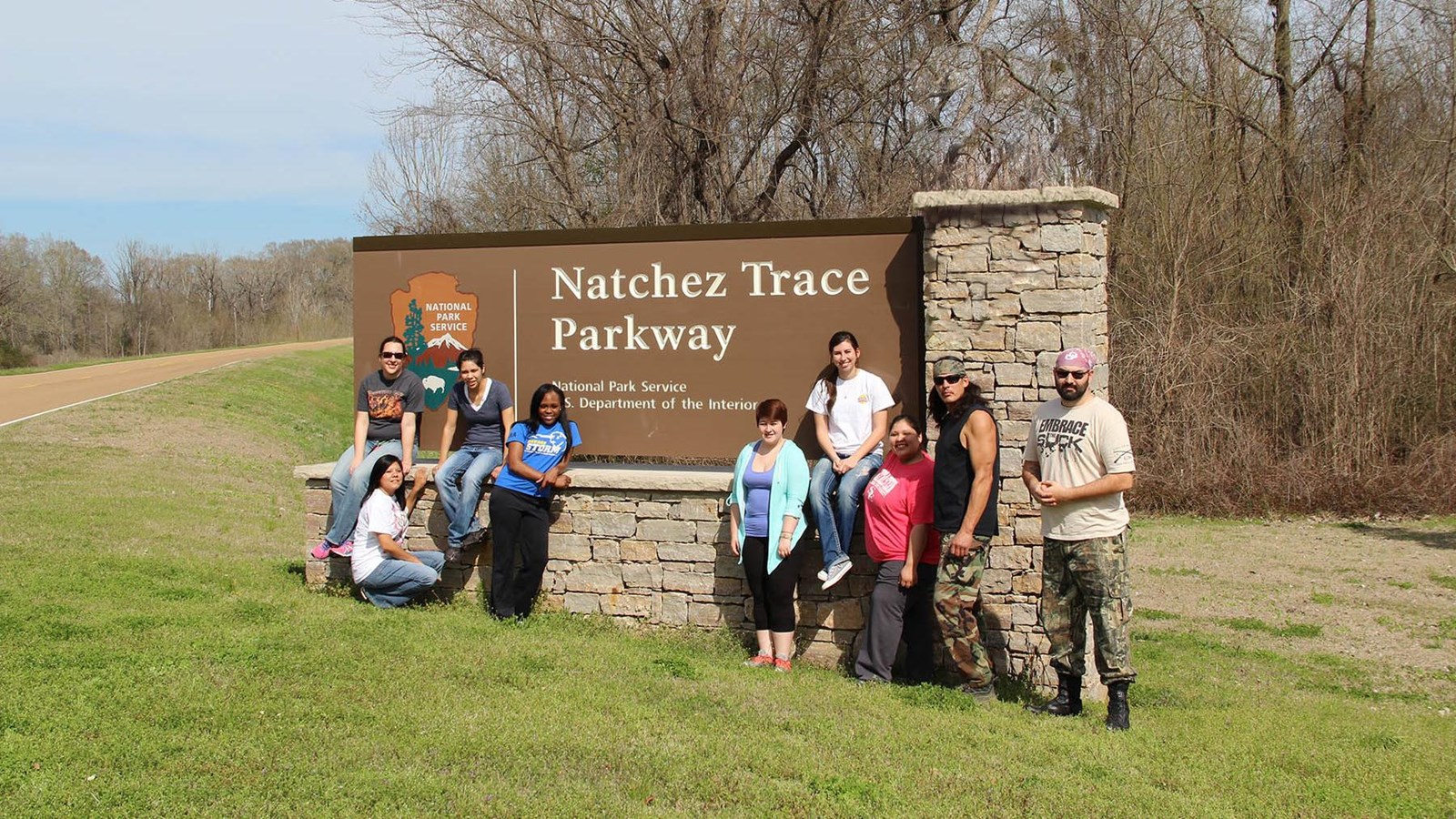 NPS sign, Natchez Trace Parkway with 10 American Indian students standing by it. One on the pillar.