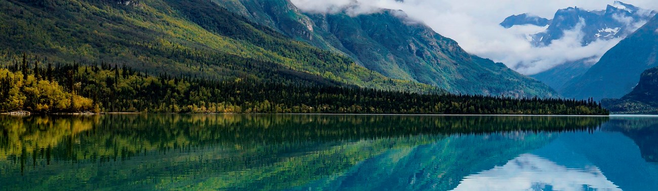 Mountains and yellow trees reflect in blue waters