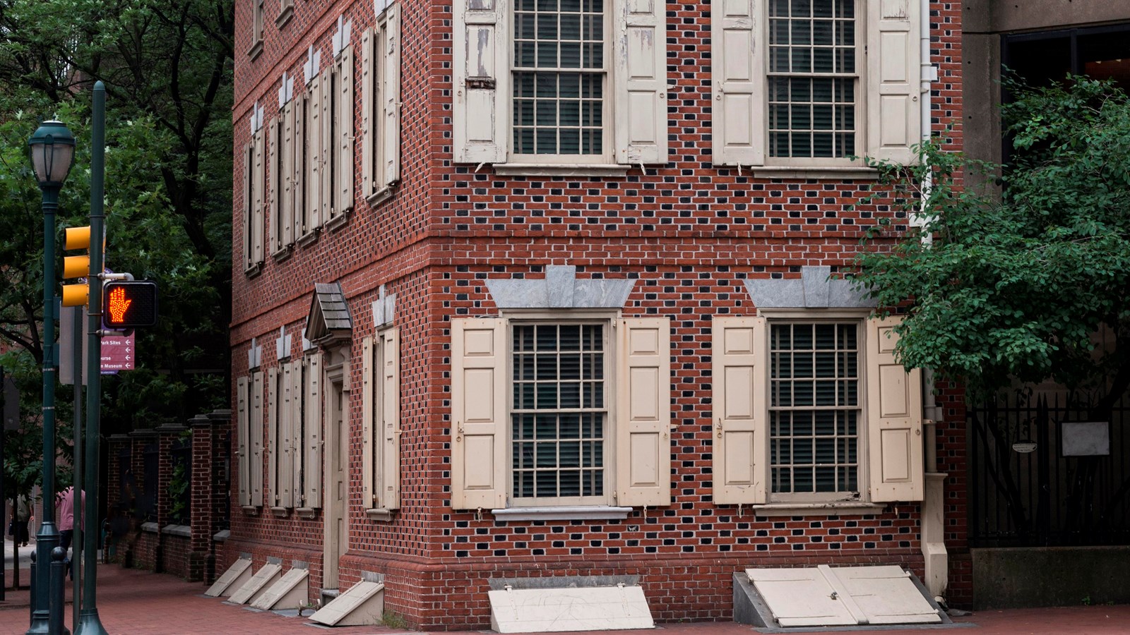 A color photo of a three story brick row house on the corner of a modern street