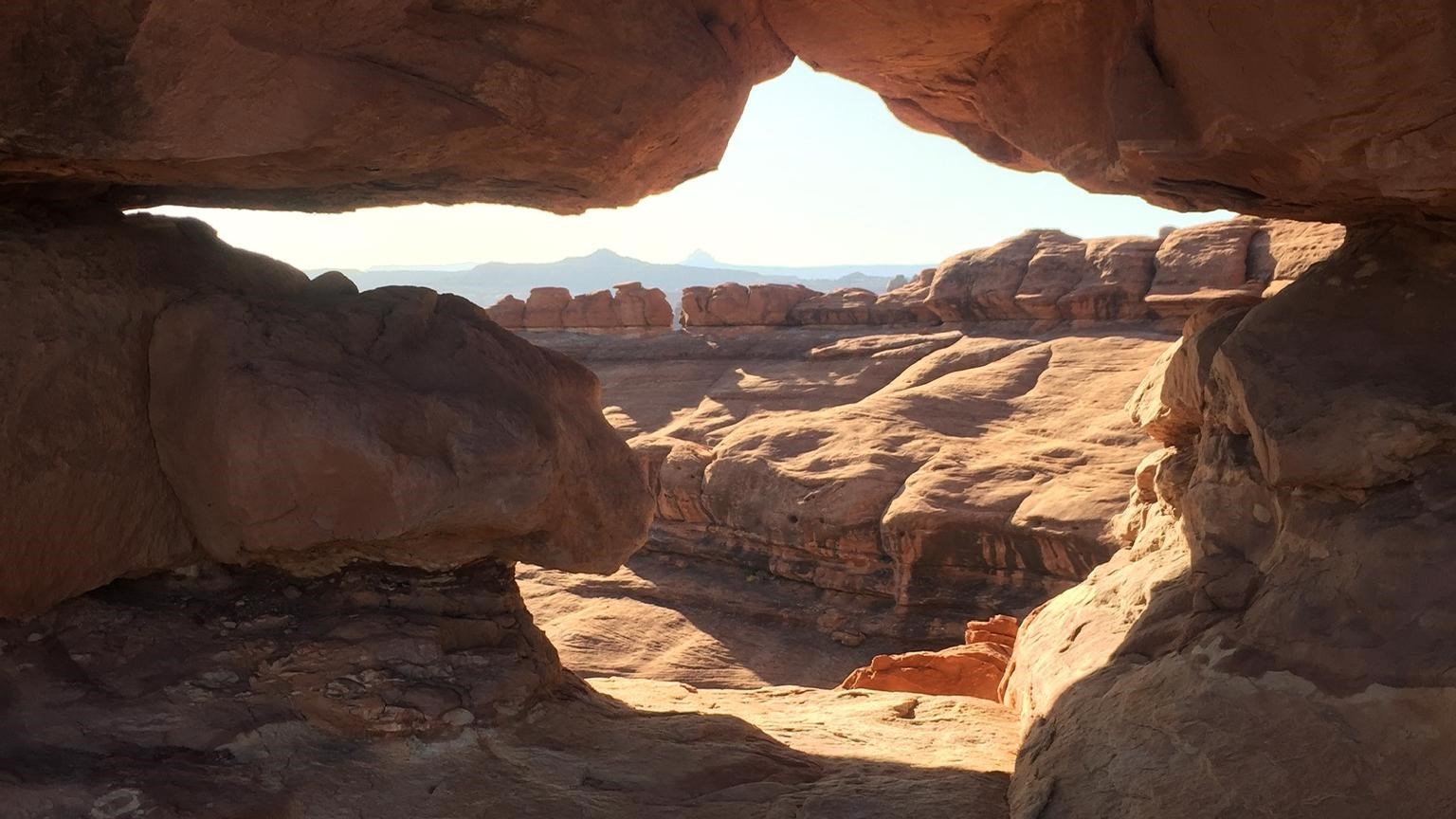 Canyons seen through a small opening along a sandstone wall