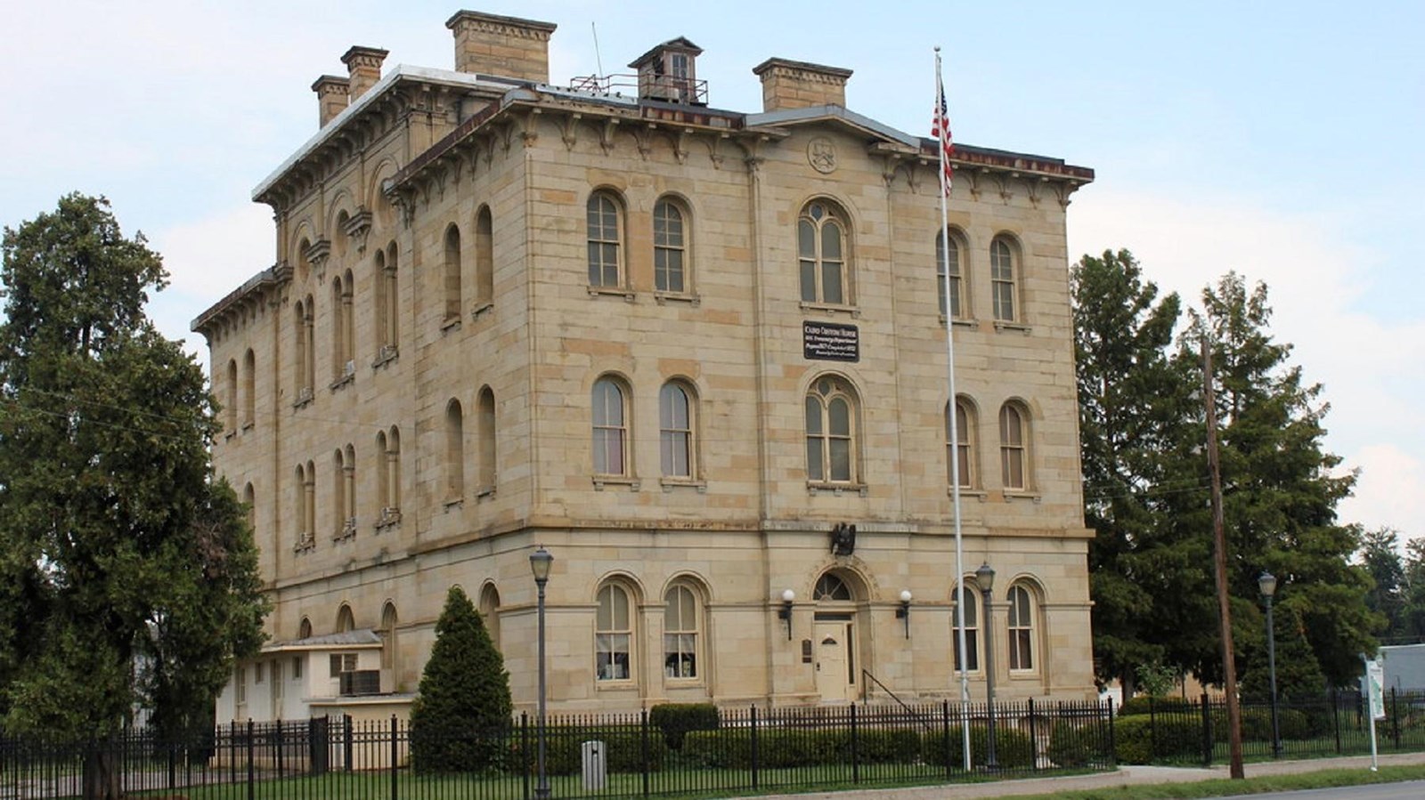 Tan brick three story building with many arched windows and four chimneys