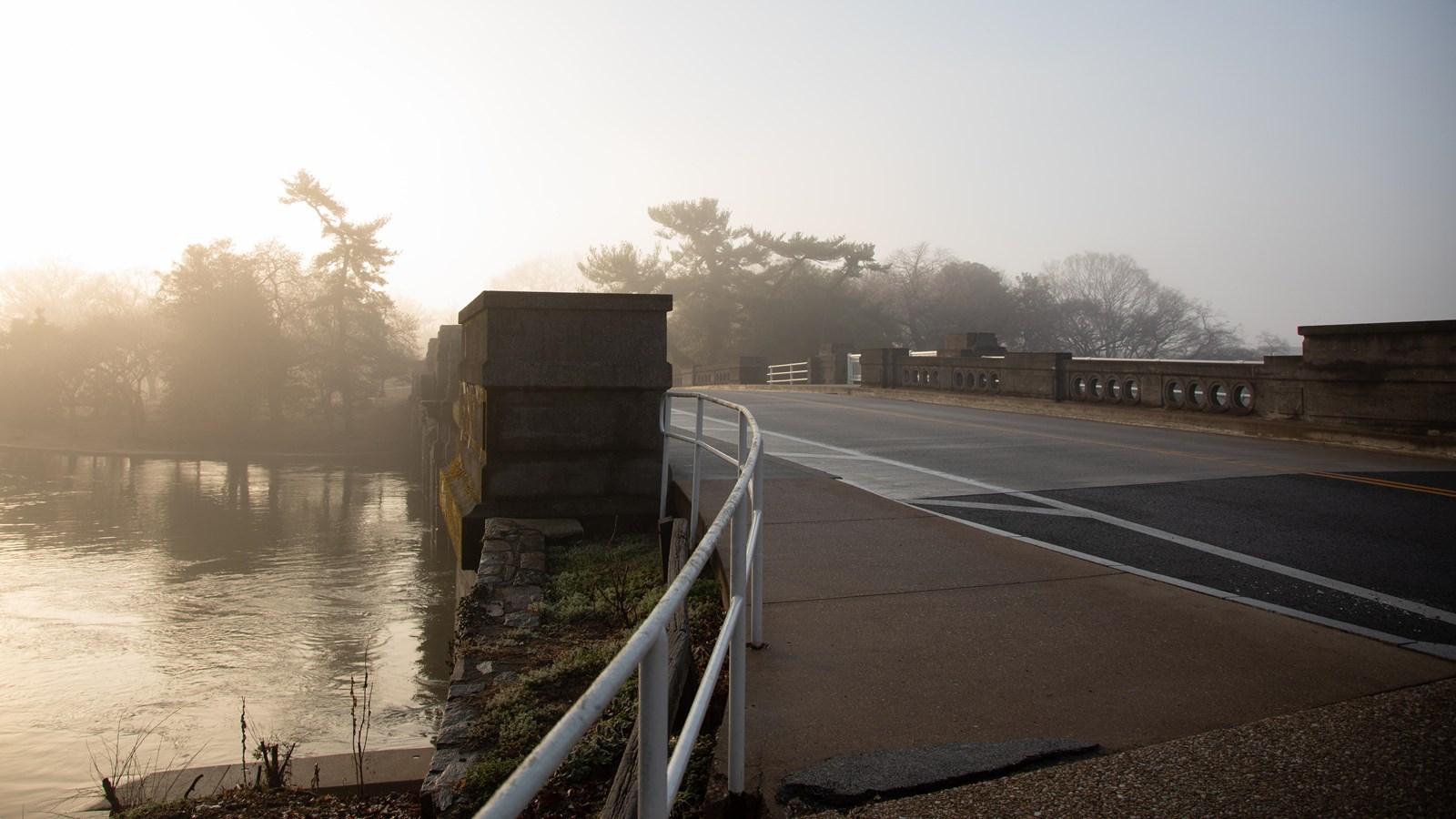 A car and foot bridge over the Potomac river at sunrise.  