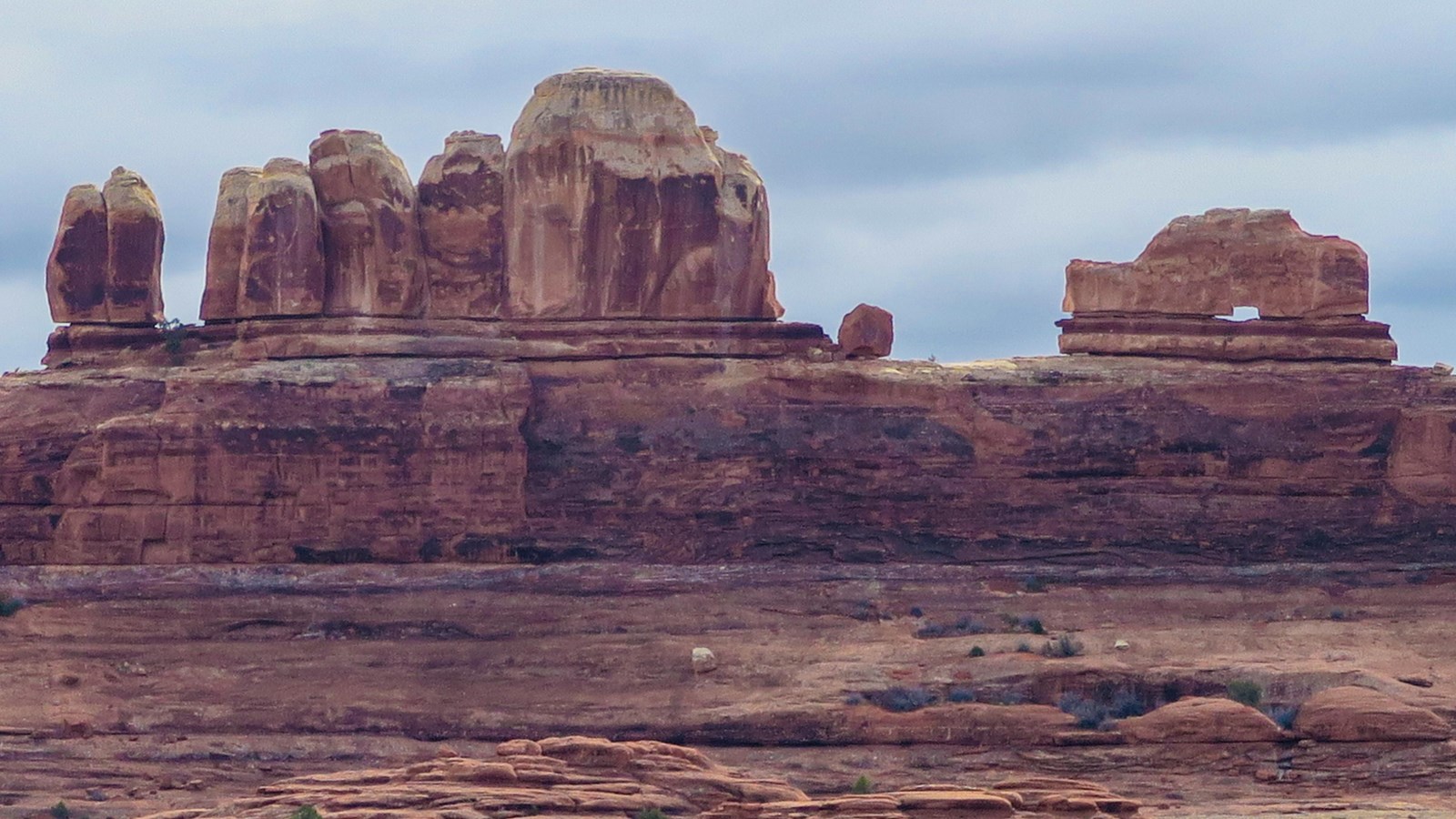 A sandstone feature that resembles a wooden clog shoe sits atop a canyon wall