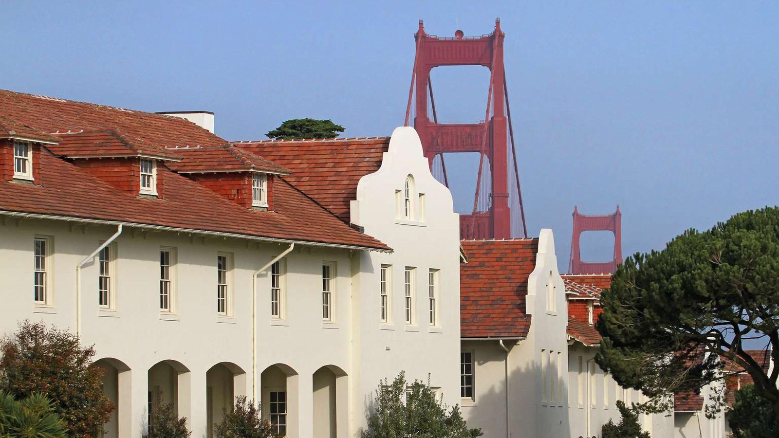 Mission Revival buildings along the parade ground with the Golden Gate Bridge in the background.