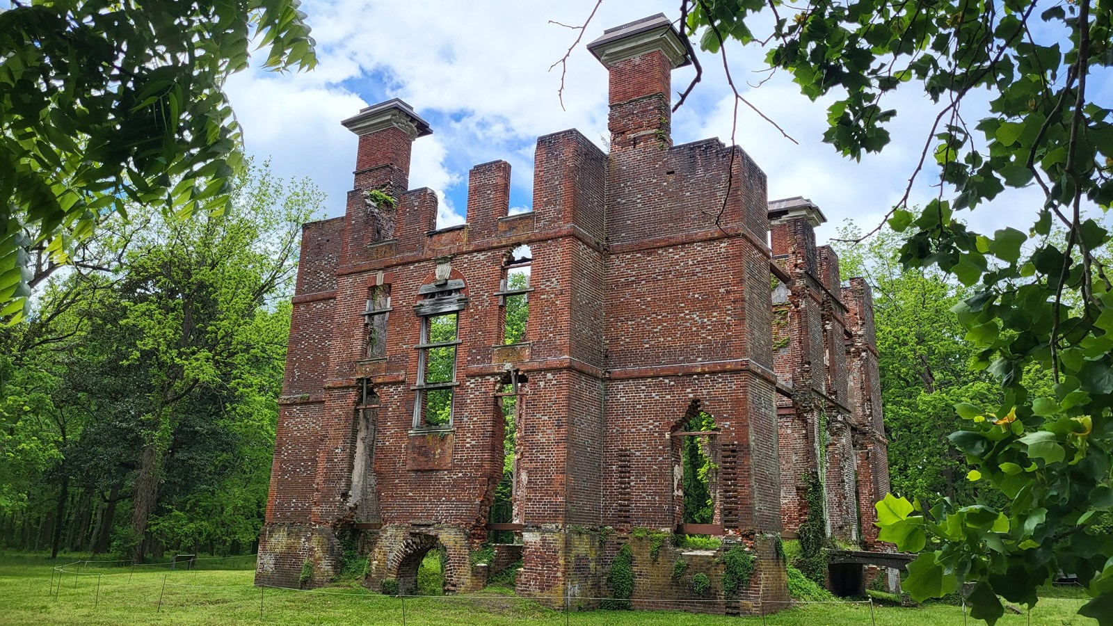 Ruin of a historical brick building surrounded by greenery.