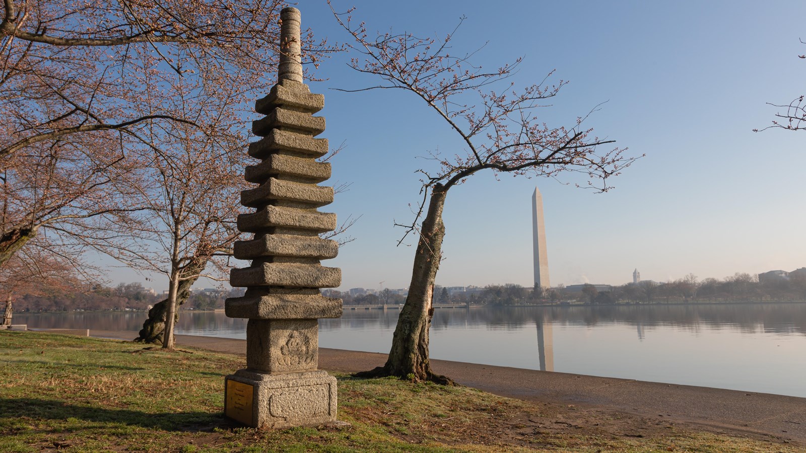 A stone statue at sunrise with the Washington memorial in the background. 