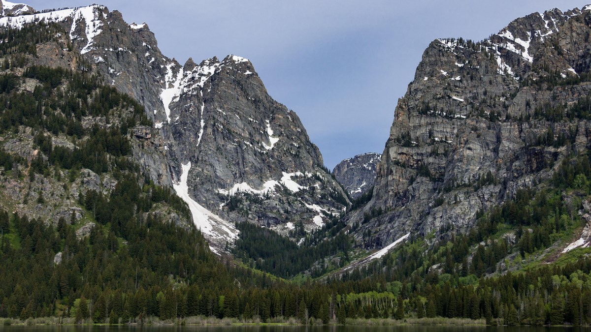 A rocky, mountain canyon sits across a calm lake.