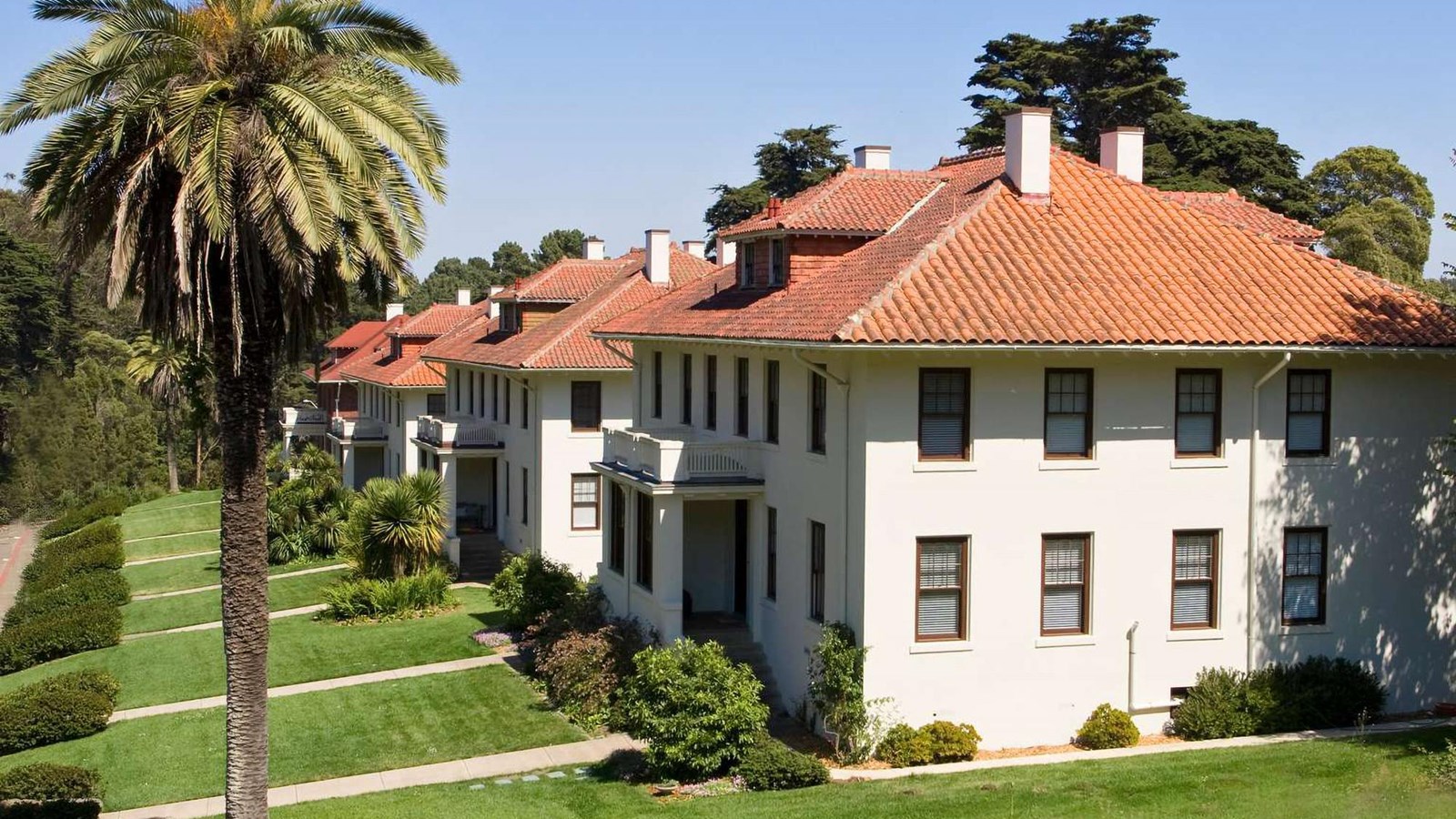 Row of white stucco houses with red tile roofs.