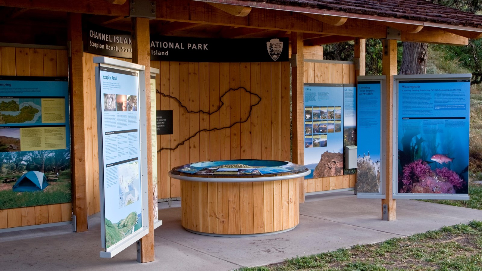 signs and a relief map under a roof with a cement slab.