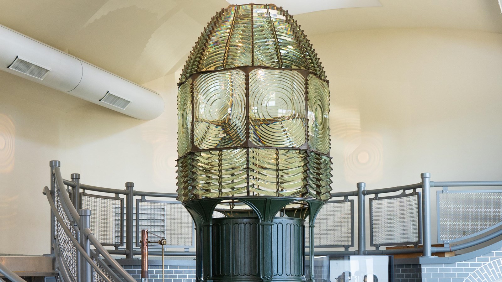 A large mechanical device with intricate glass housing and a metal base surrounded by a platform.