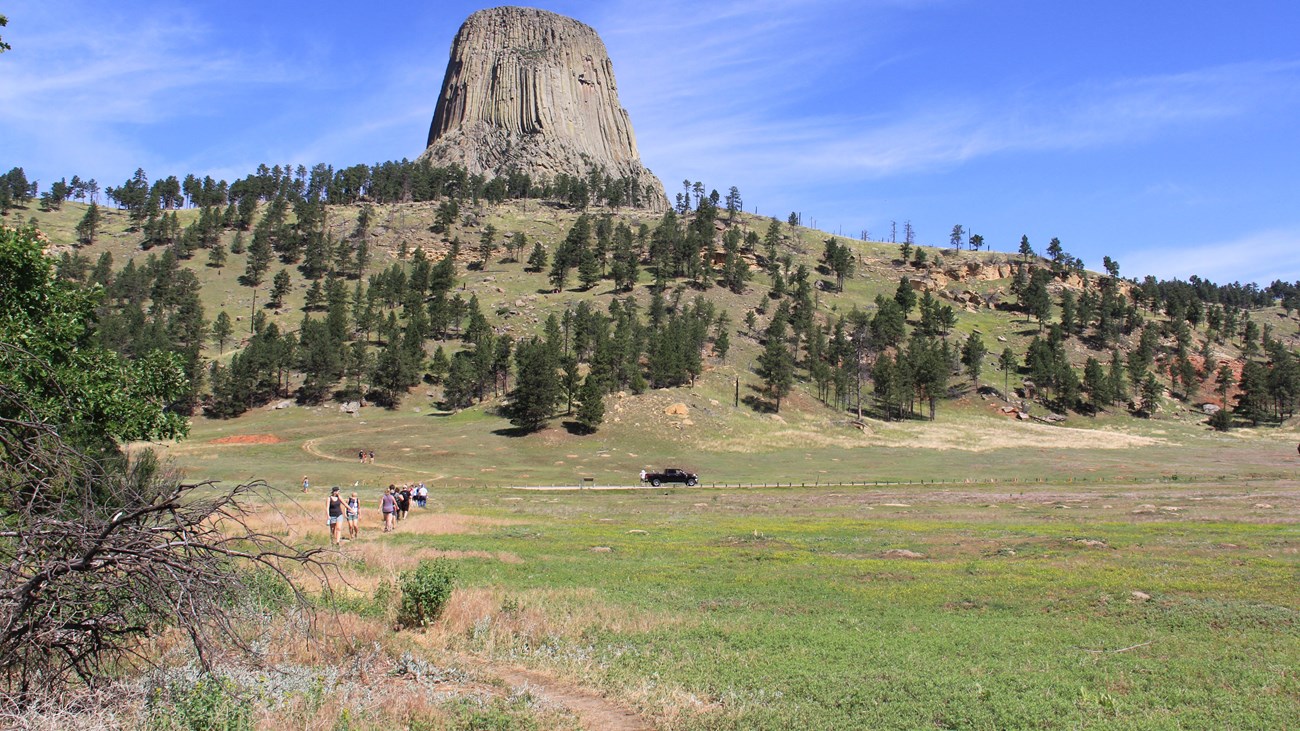 people walking along a dirt path through the prairie dog town, Devils Tower in the background