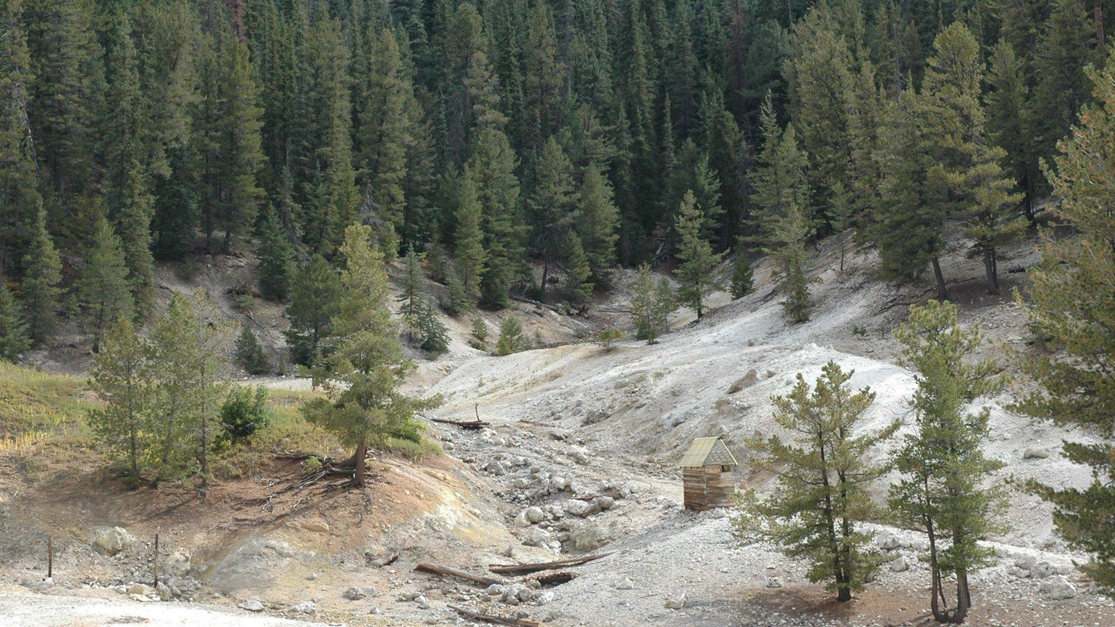 Hills of bleached gravel and soil with sparse vegetation.