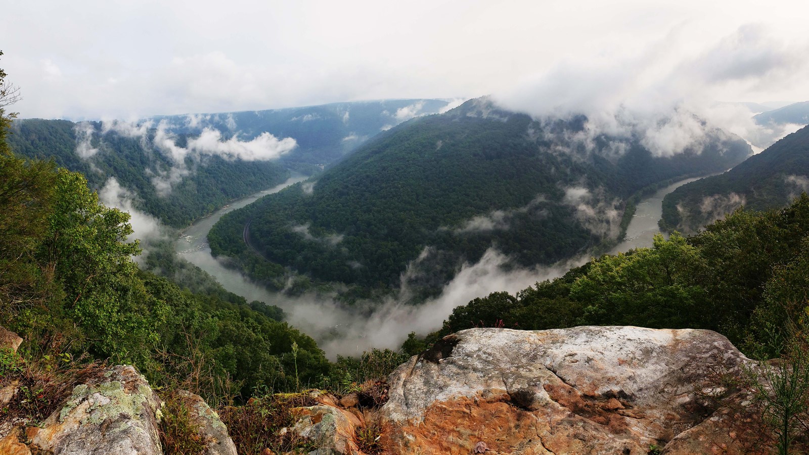 a view into a deep river gorge with clouds