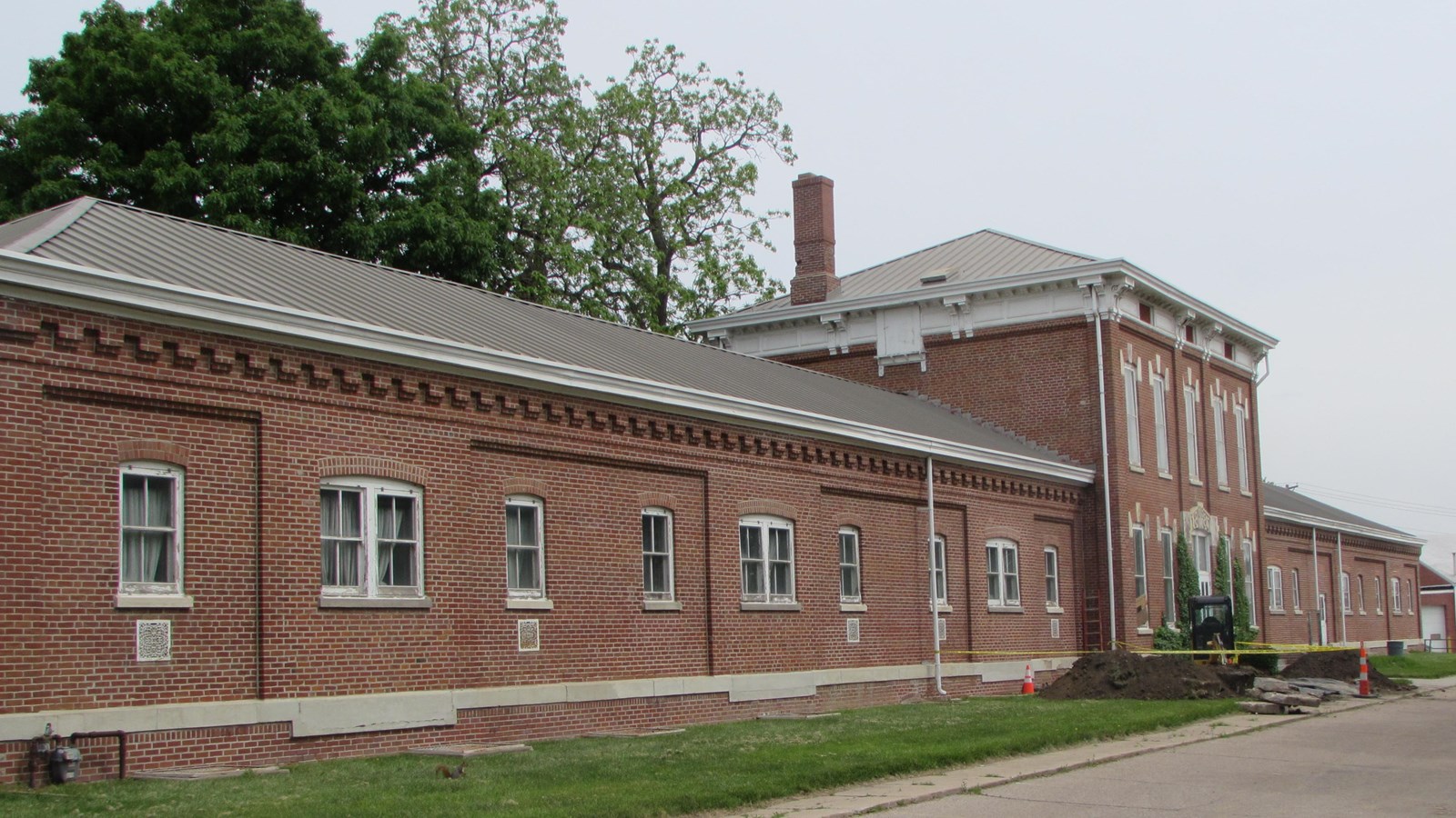 Linear warehouse with central two-story body and two long one story wings. Windows throughout.