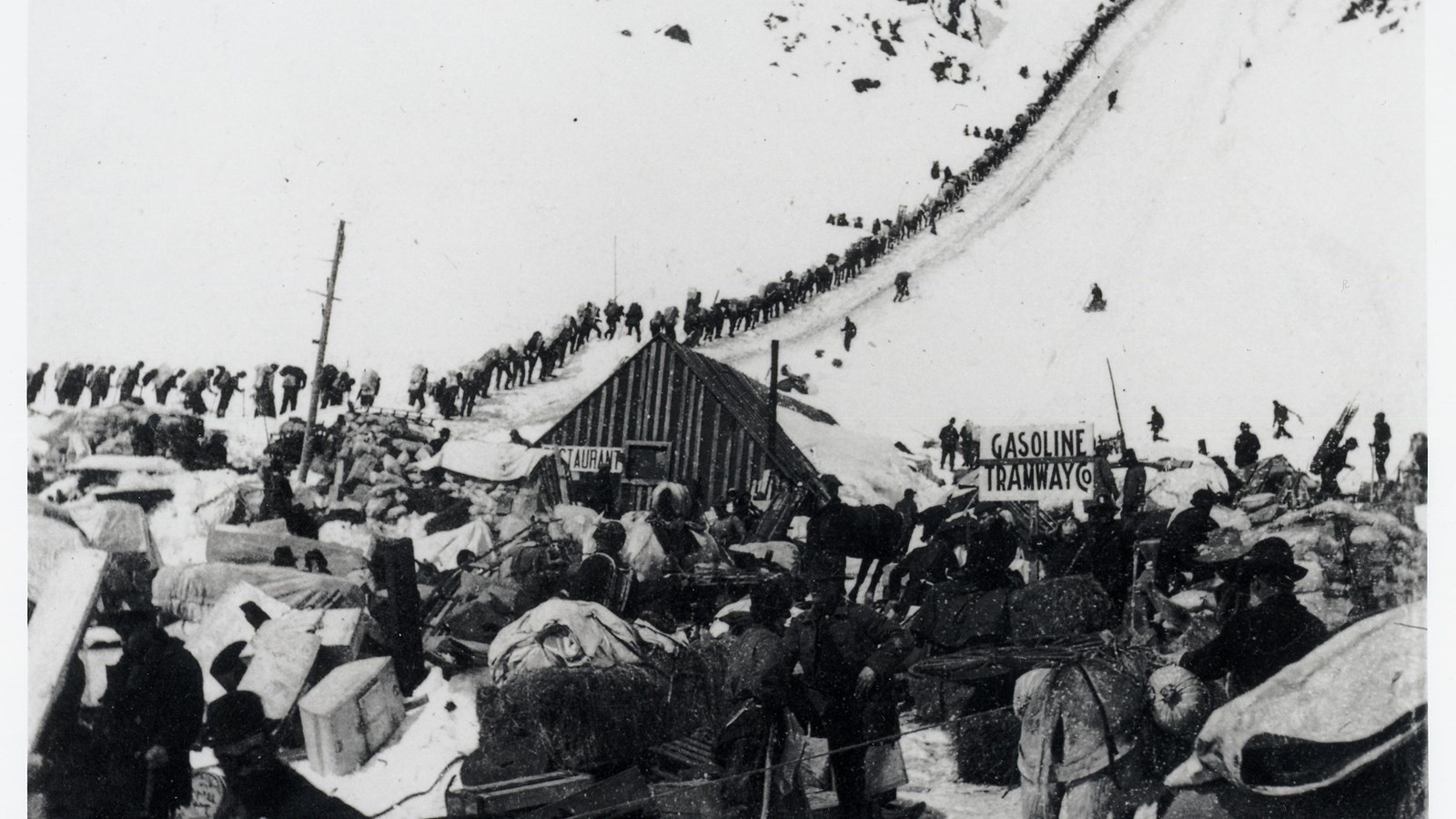 Historic tent city and a single file line of people hiking the Golden Stairs over Chilkoot Pass