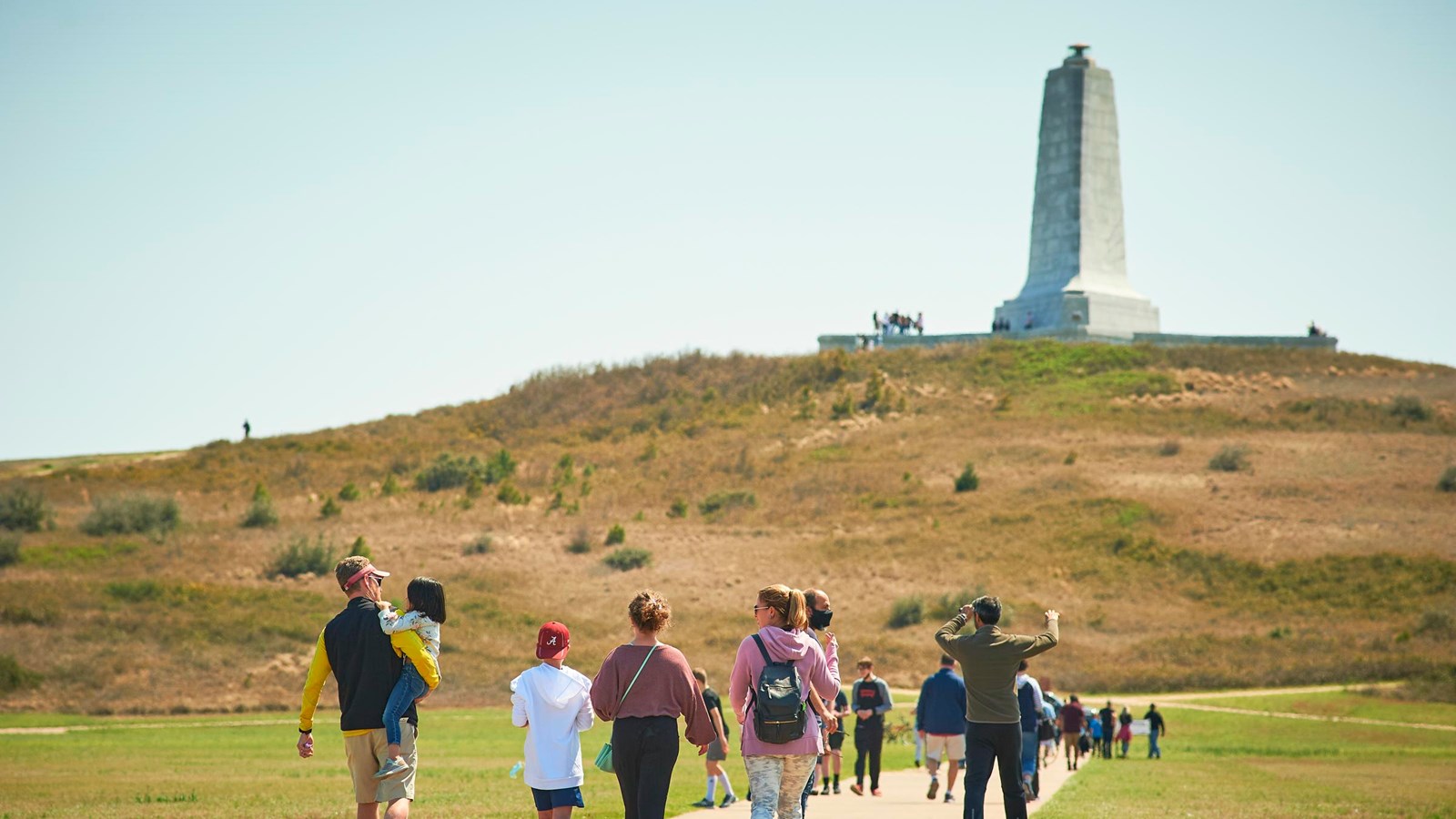Visitors walk along the path towards the monument in the distance.