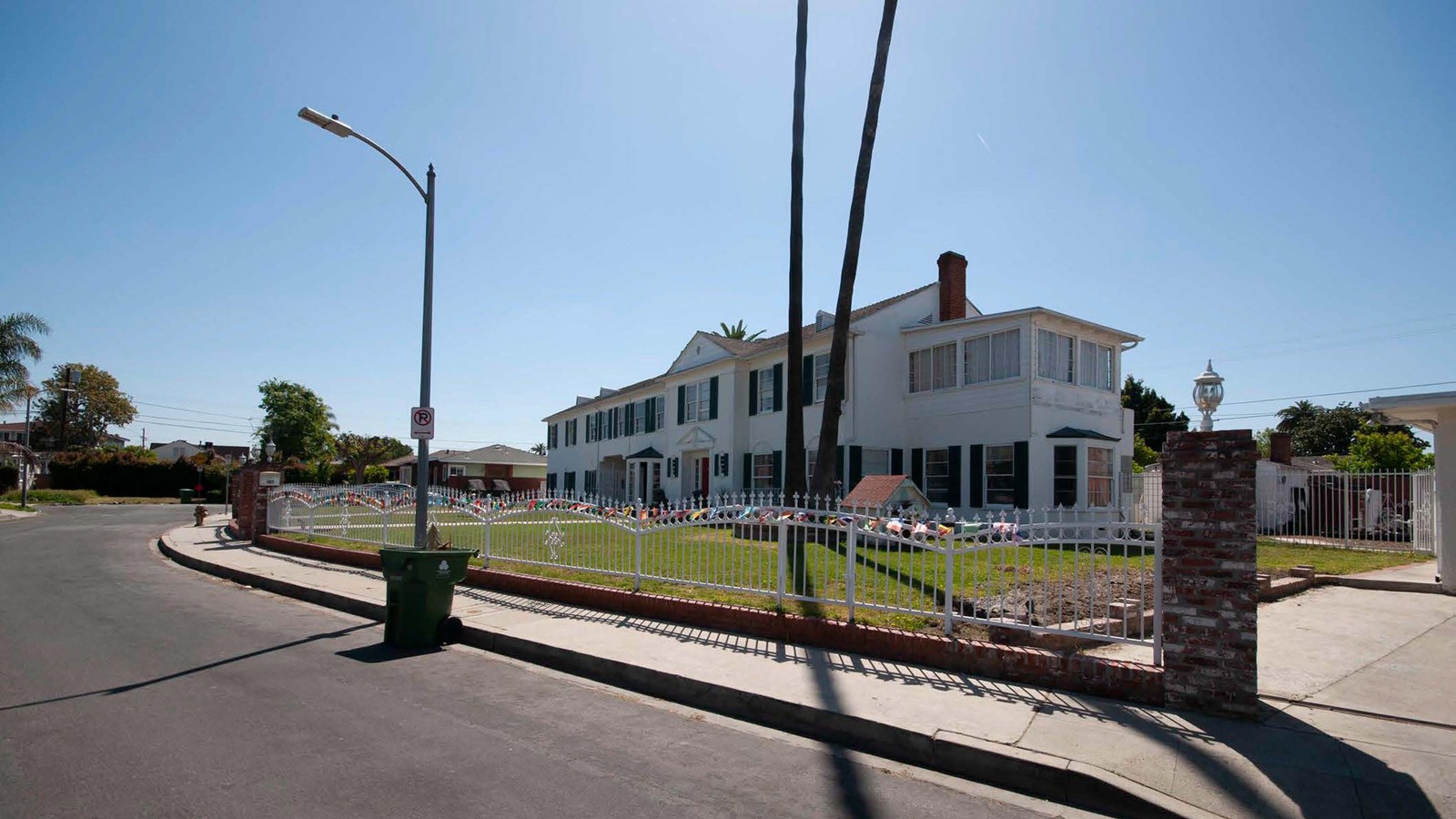 large two-story white house with a front yard and white metal fence 