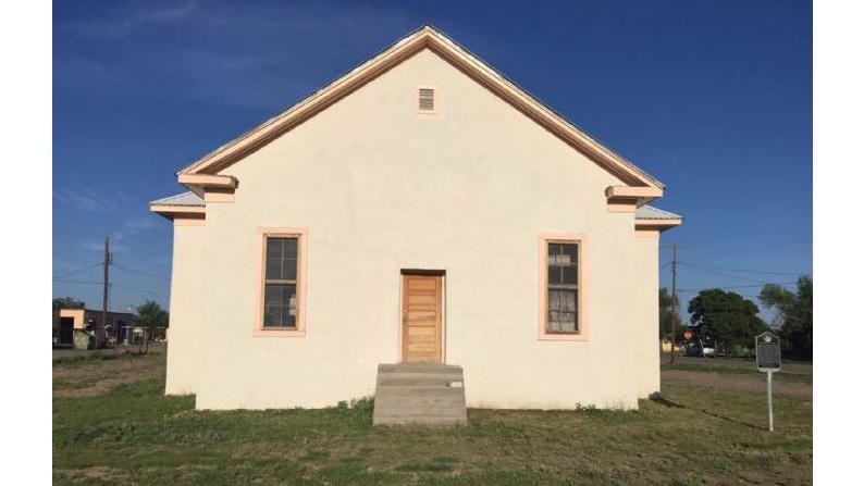 plain house with two small windows on either side of the centered door. Steps lead up to the door