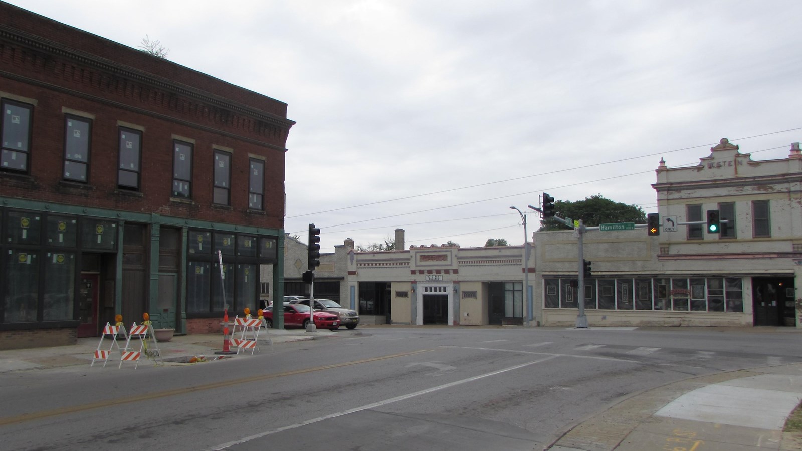 Two-story brick commercial building at corner with one-story commercial buildings opposite.
