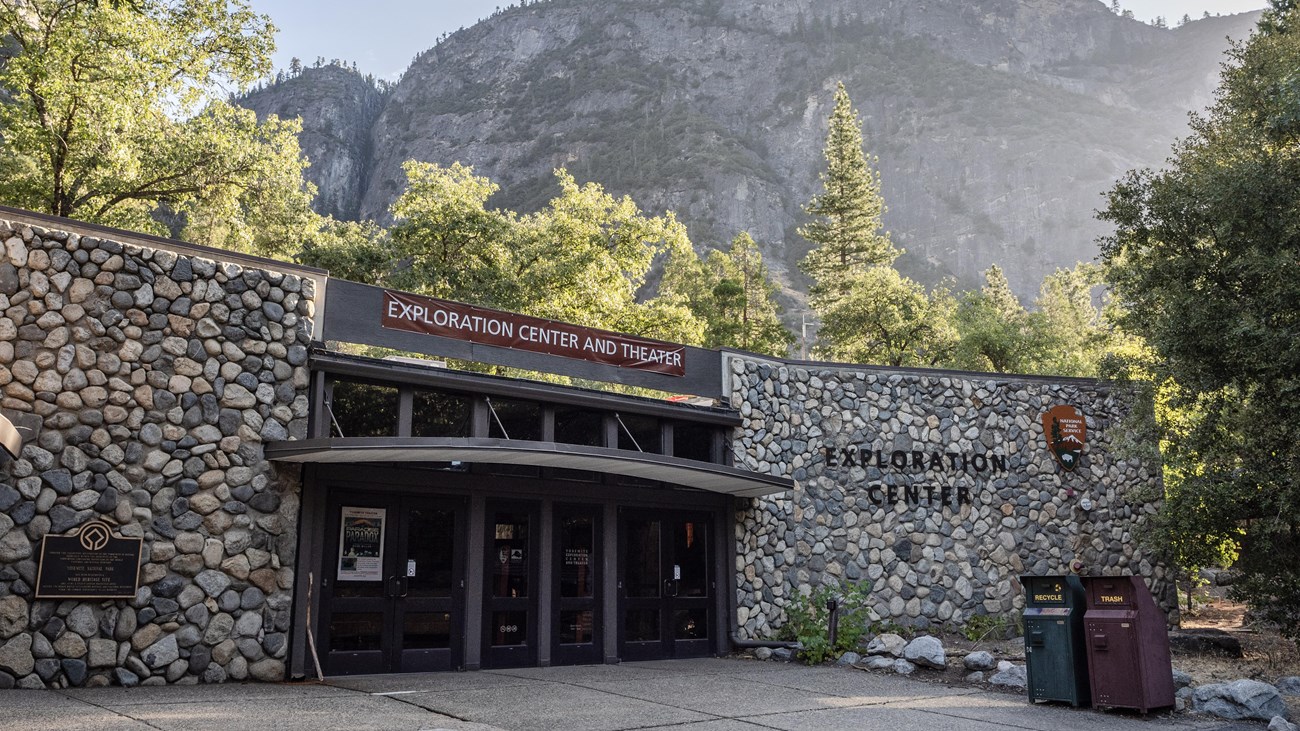 A building with glass double doors and river rock walls surrounding both sides