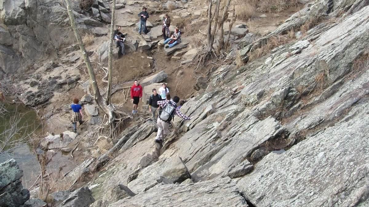 Hikers scrambling up a rock face.