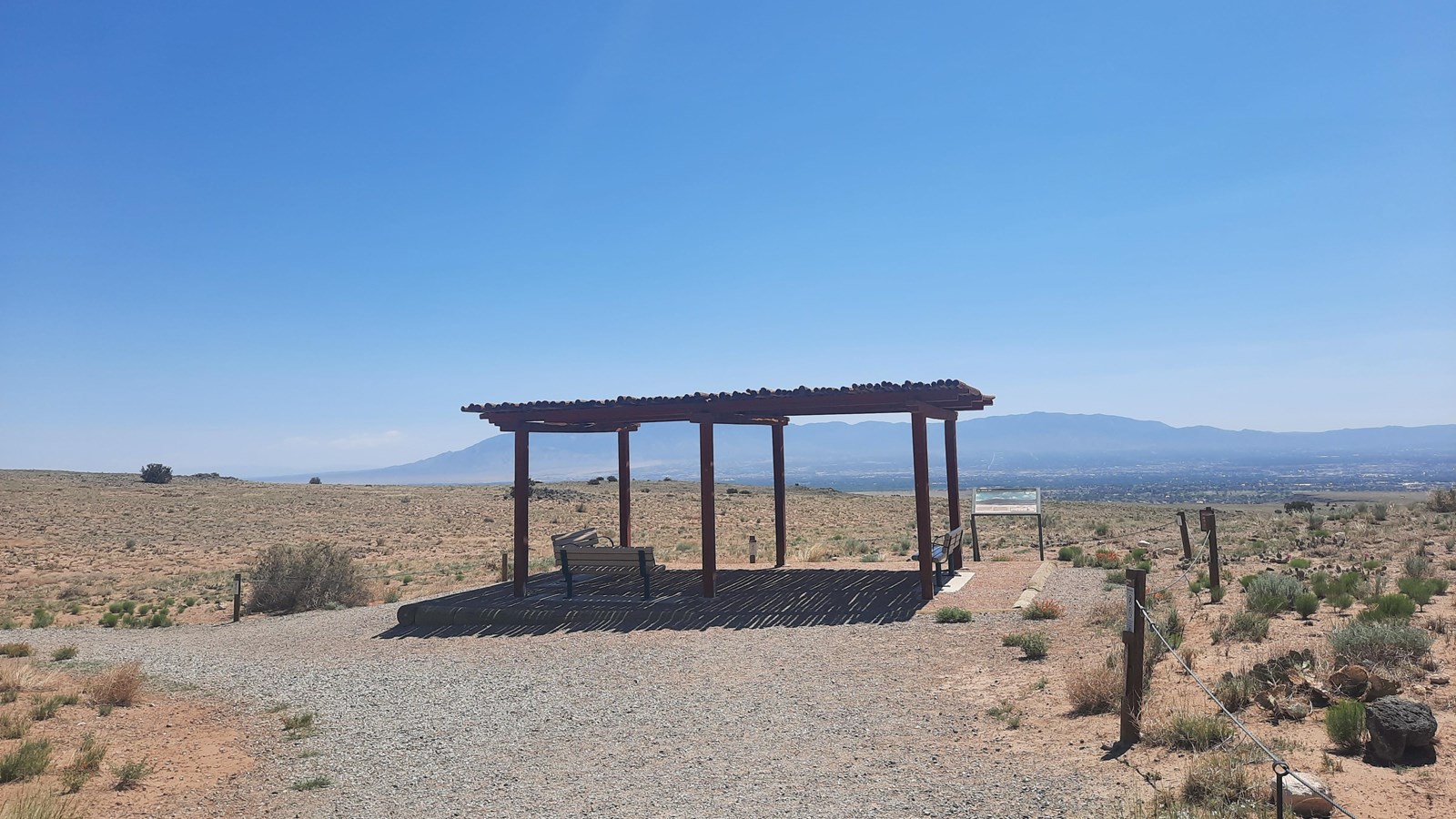 A shade shelter at the end of a dirt path in a desert landscape.