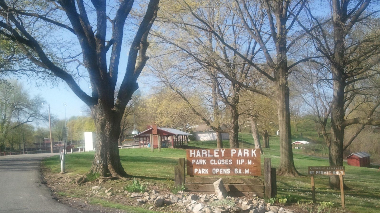 A road leads into a grassy park with shelters.