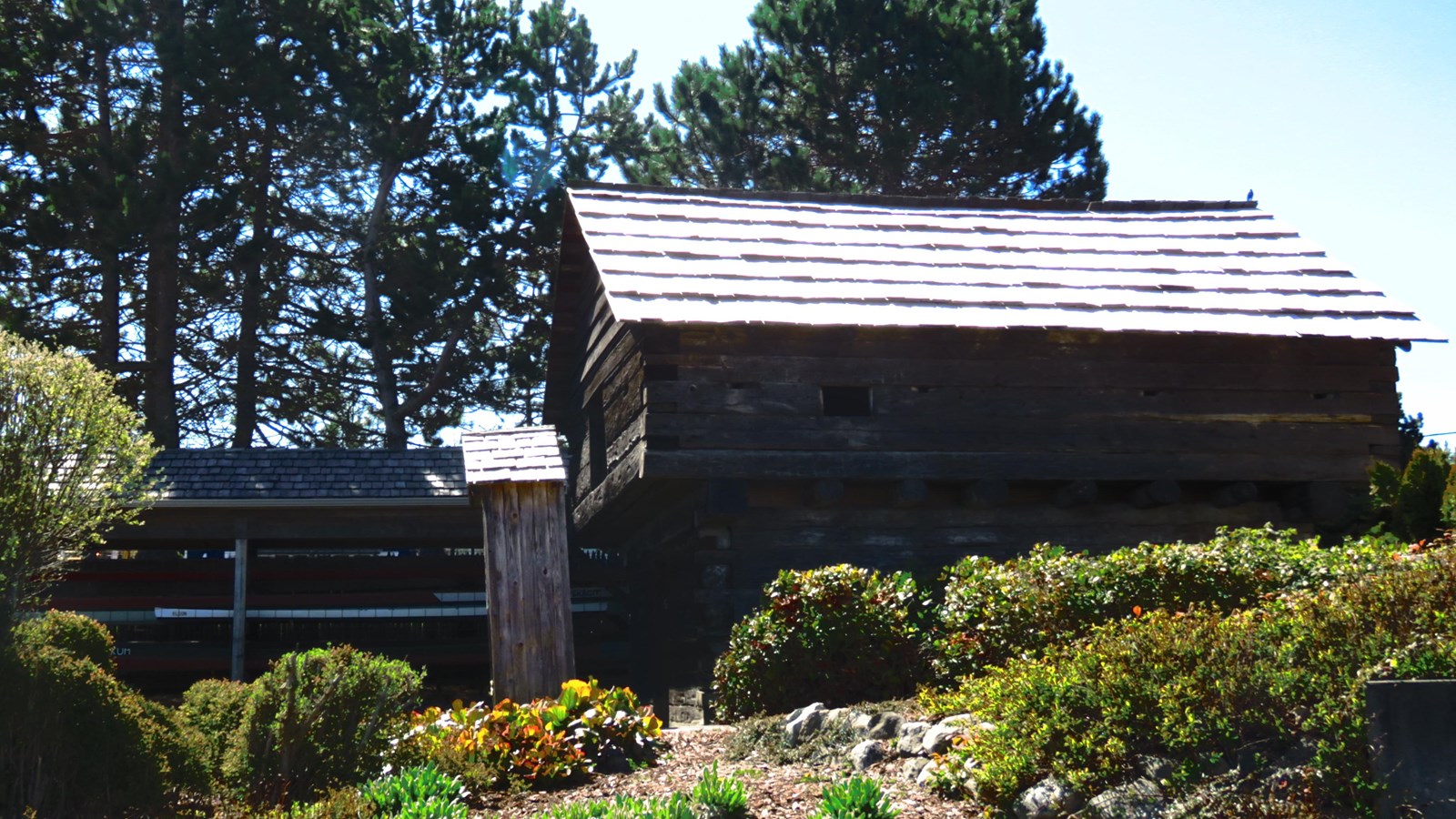 Old log building used as a fortress behind shrubbery.