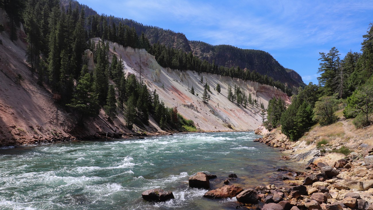 A river flows through a canyon with pale, sloping walls.