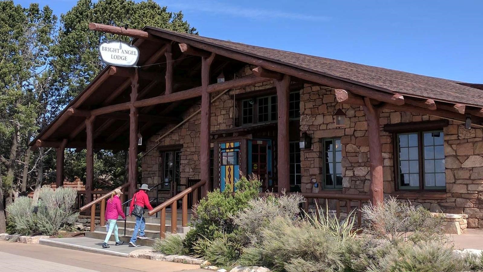 A wooden and stone building with a short set of steps leading up to a peaked roof and entryway.