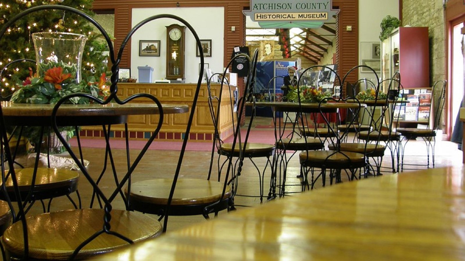 Empty cafe chairs inside a mall hallway; the entrance to the musem in in the background 