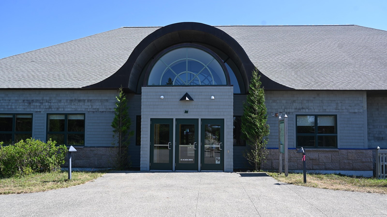 A grey wooden building with a rounded top and large windows 