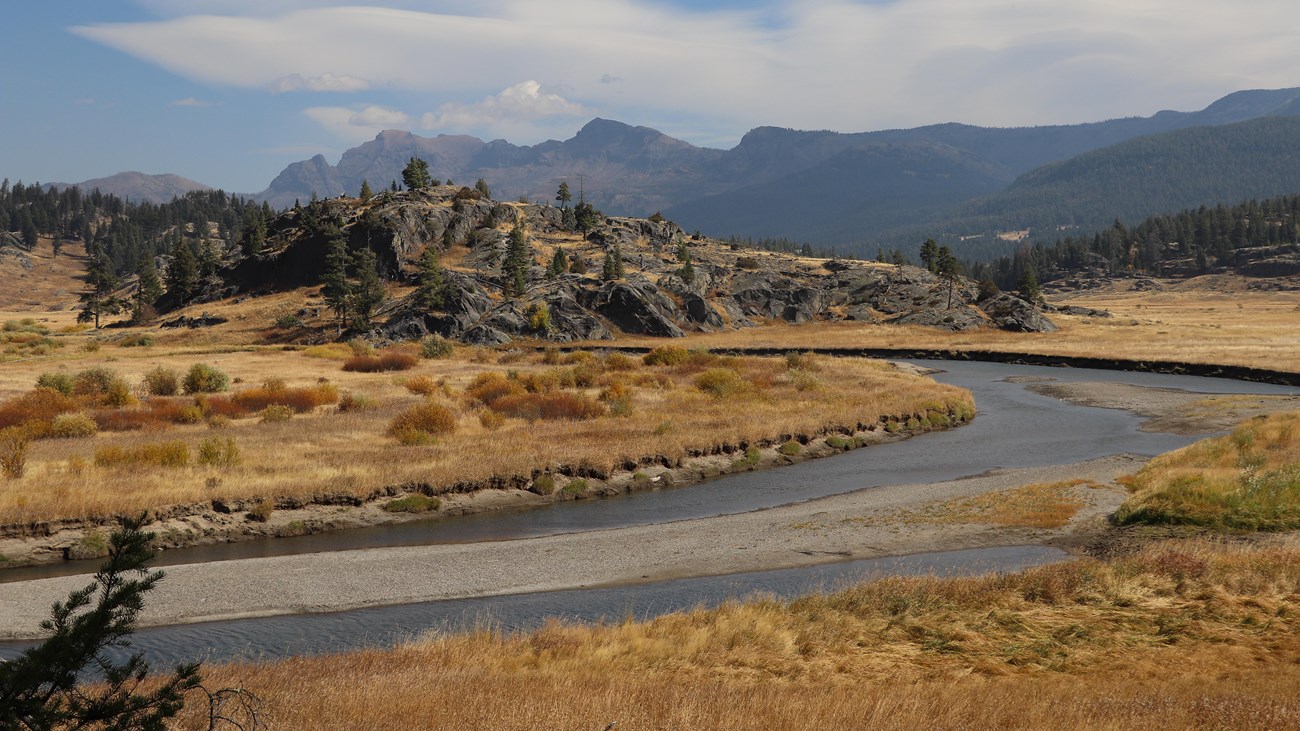 A creek meanders past a rocky outcropping.