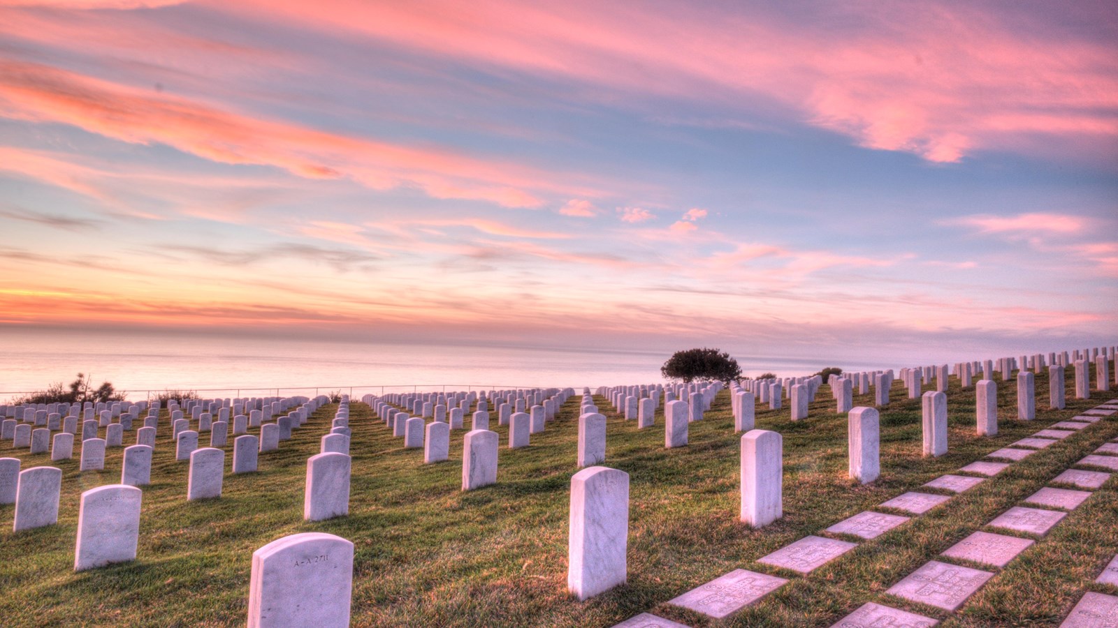 A row of gravestones in a cemetery at sunset