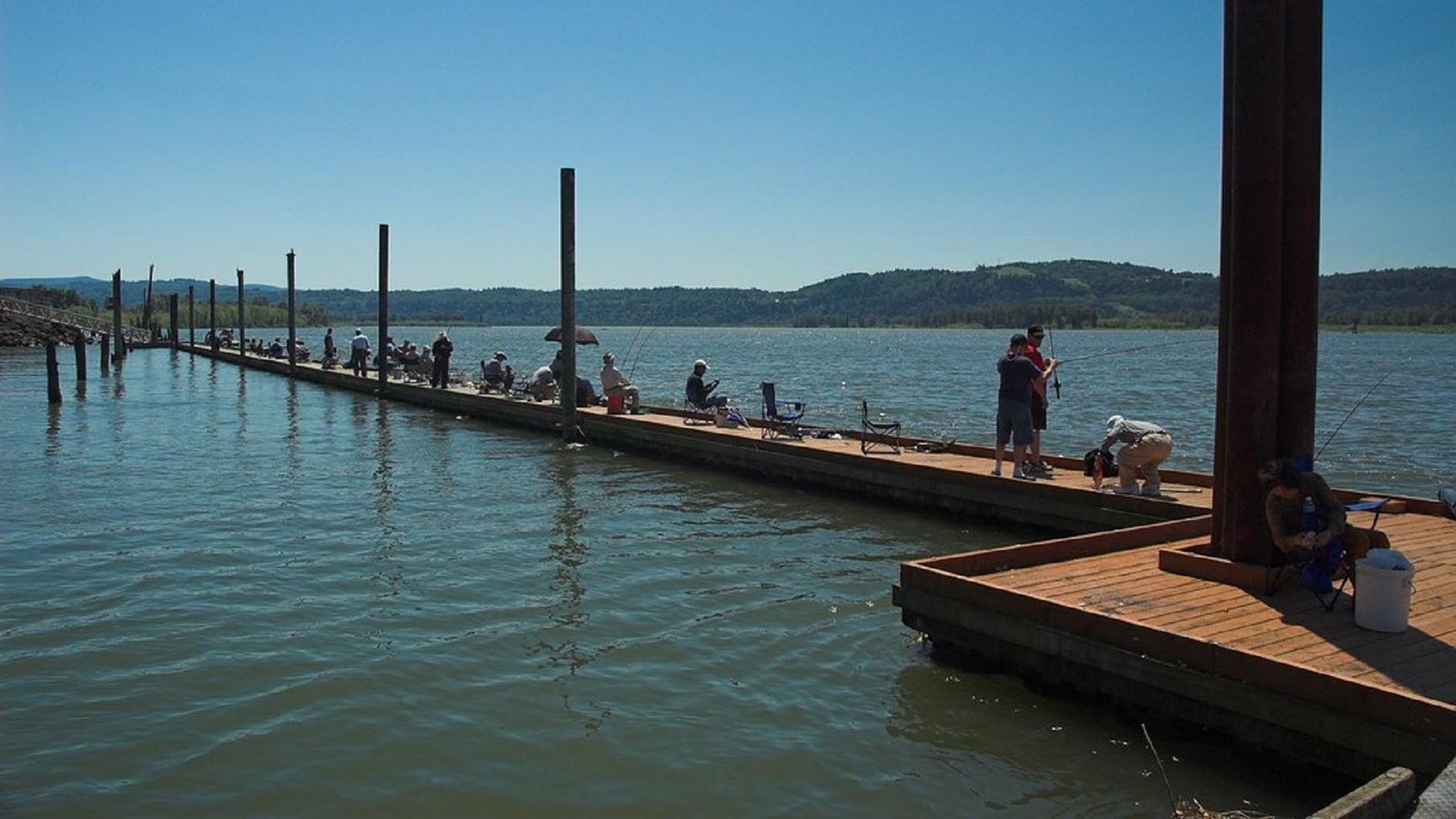 Fishermen along a dock stretching out into the water.