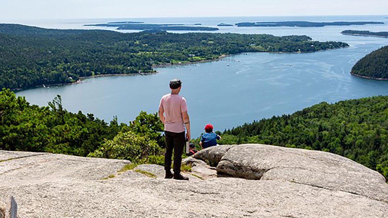 Visitors overlook islands from a mountain summit.