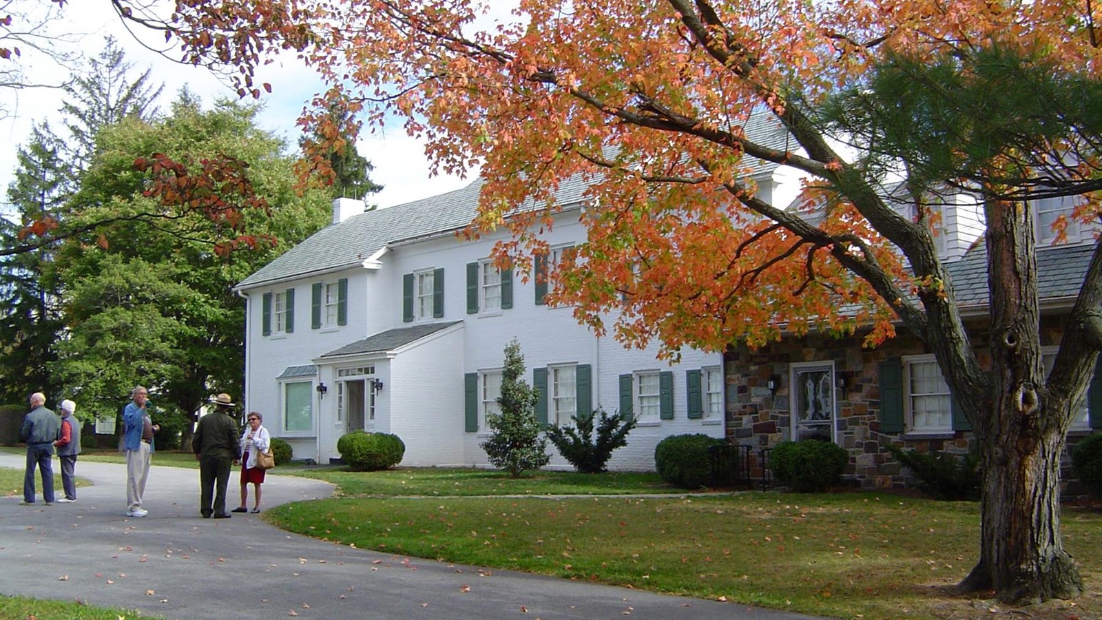 A white farmhouse with visitors gathered outside