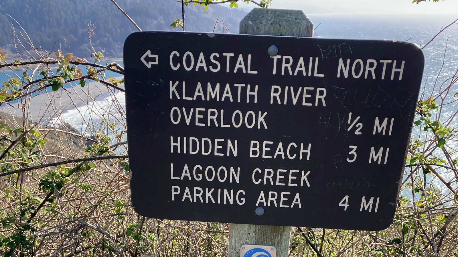 A wood sign listing trails and mileages