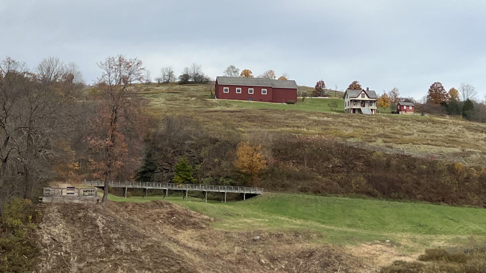 A view across the empty lakebed with a farm house and barn on the hillside.