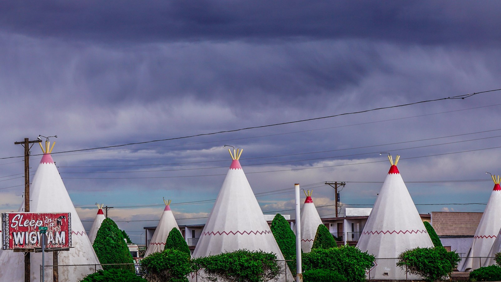 Seven large white cone shaped wigwams with red trim. A red sign reads 
